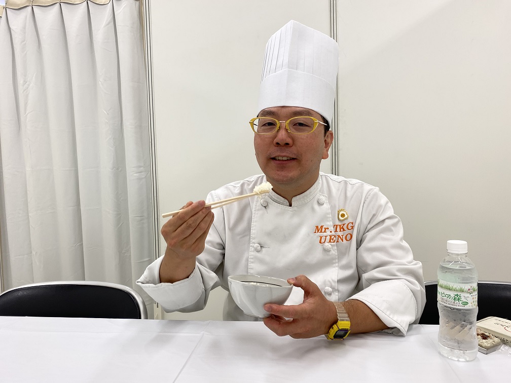たまごかけごはんけんきゅうじょ代表りじの上野さんがタニタこまちを試食する様子の写真